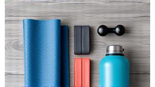 Fitness gear layout with resistance bands, a yoga mat, and small weights on a clean floor.