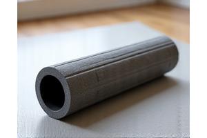 Ergonomic foam roller on a yoga mat, suggesting recovery after exercise.